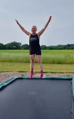 An ecstatic retreat participant jumping with joy on a sunken trampoline, expressing the freedom and exhilaration felt during the retreat.