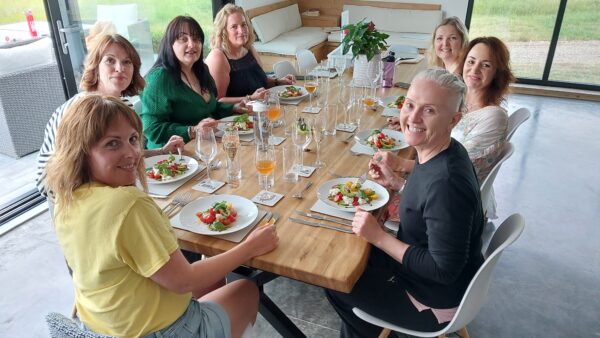 Guests gathered around the dinner table, smiling and about to enjoy a nutritious and delicious meal prepared by our private chef during the retreat