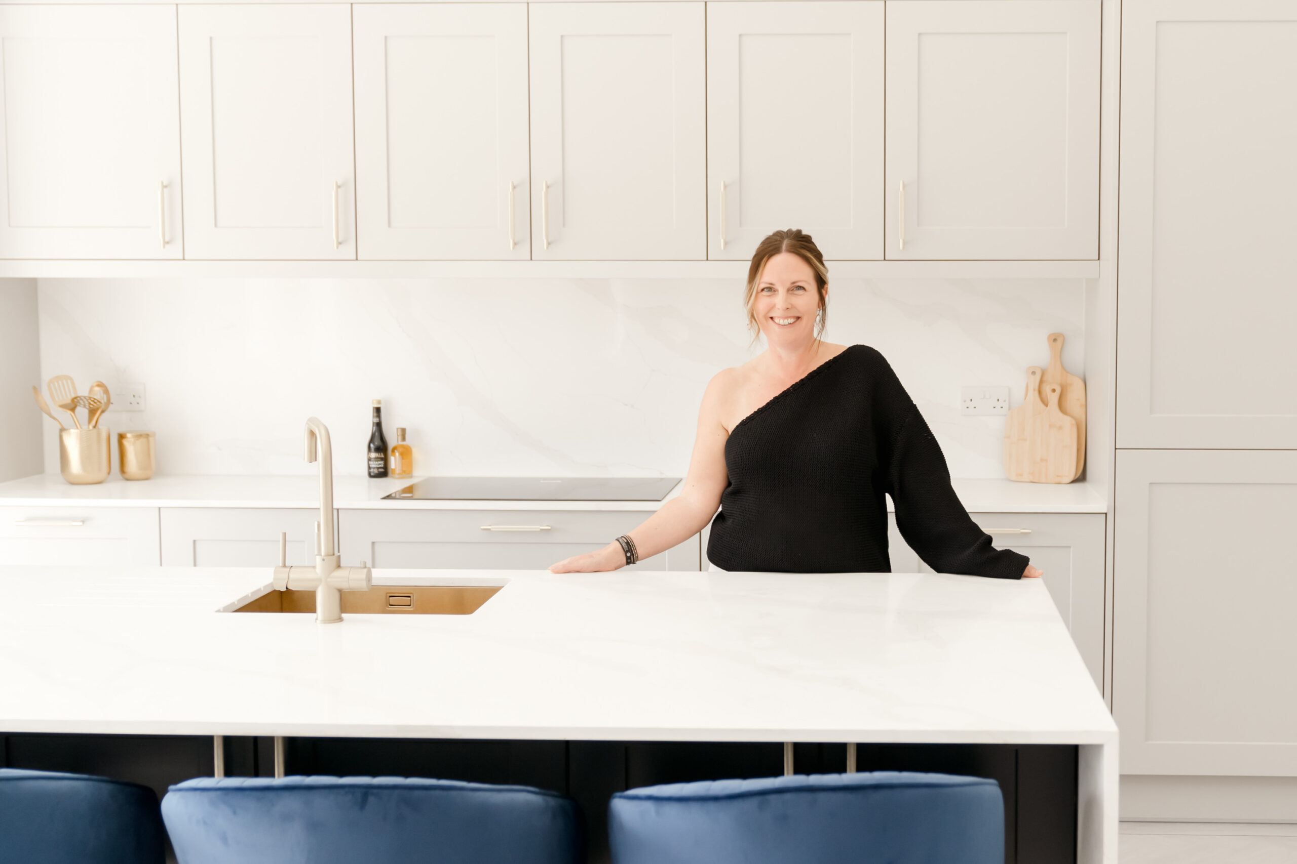Menopause coach Julie Court smiling behind kitchen island, welcoming pose.